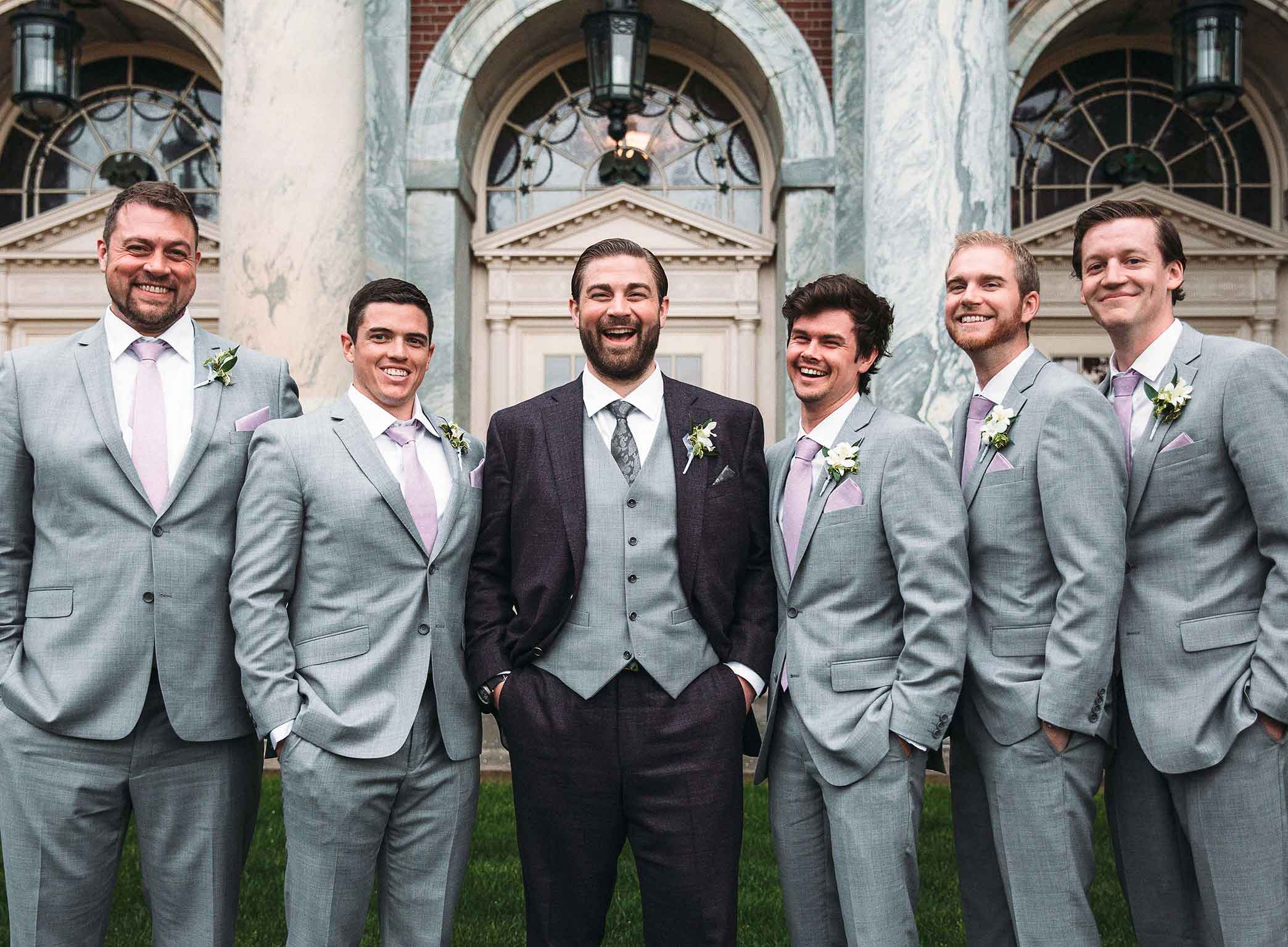a groom and his groomsmen posing for a photo outside a building