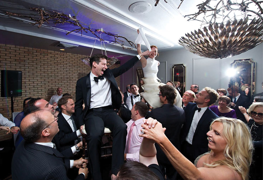Couple being lifted by wedding guests
