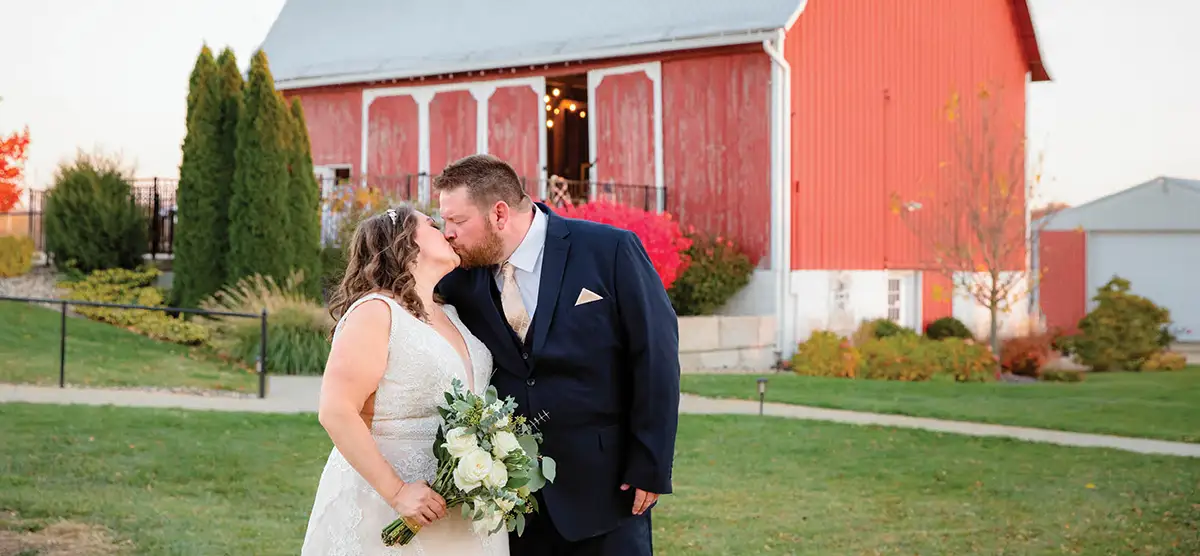 couple kiss outside The Centennial Barn