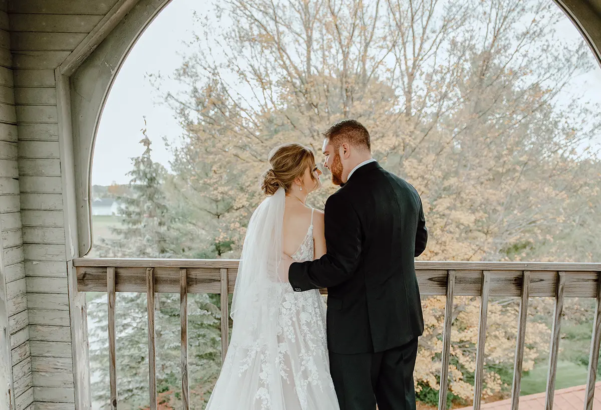Bride and groom standing as they smile at each other on a rooftop porch/ledge area inside the District 5 Schoolhouse building