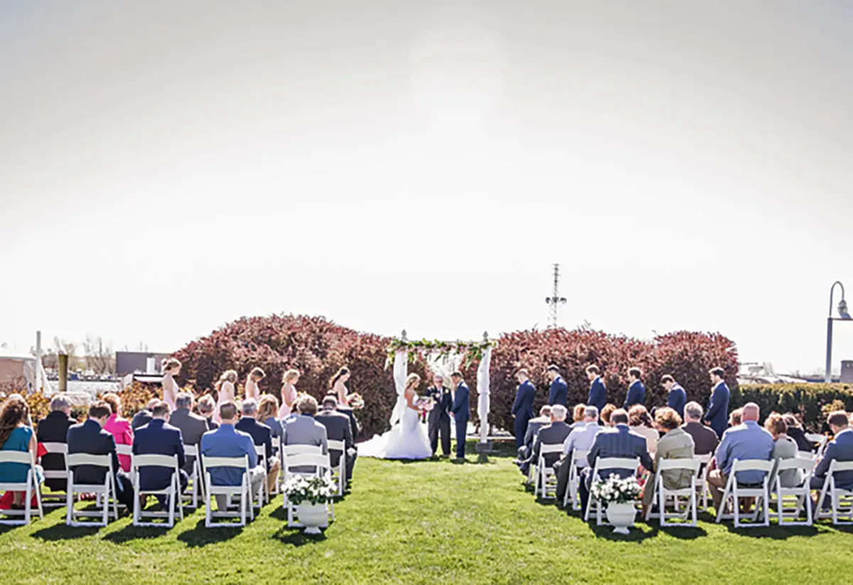 Outdoor landscape photograph of a wedding ceremony in session on a gorgeous bright sunny day at the Holiday Inn Spring Lake-Grand Haven venue