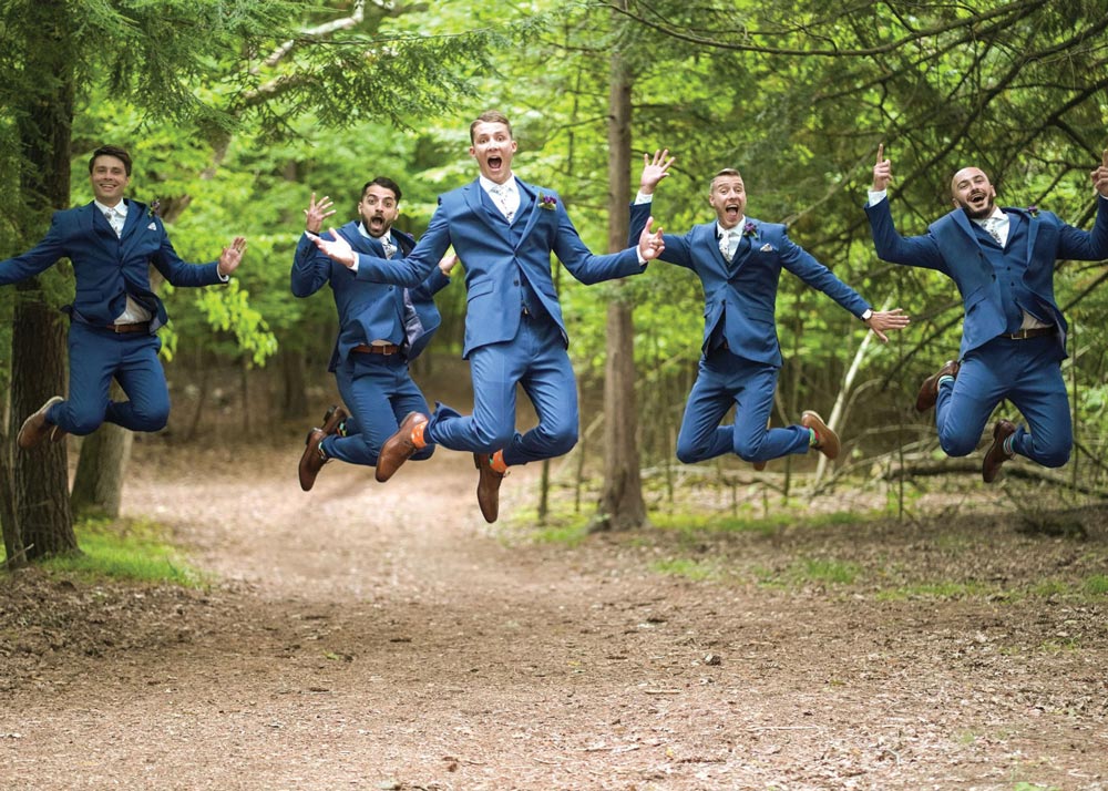 groom and his groomsman jumping in the air and smiling
