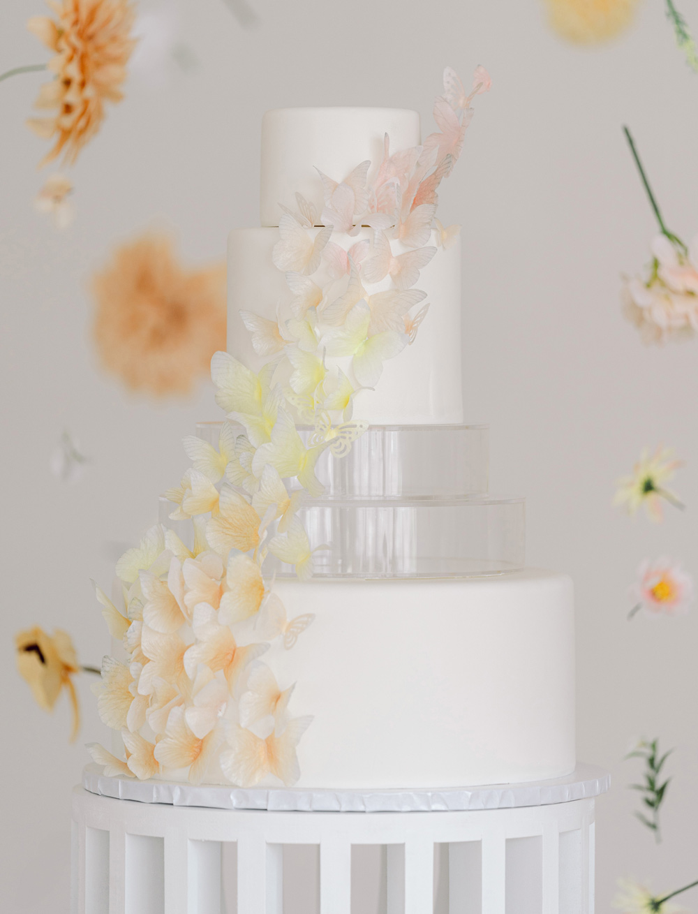 White Almond Cake layered with Swiss meringue buttercream and organic strawberry preserves, frosted in buttercream, finished with fondant, and decorated with Lucite tiers and hand cut wafer paper edible butterflies