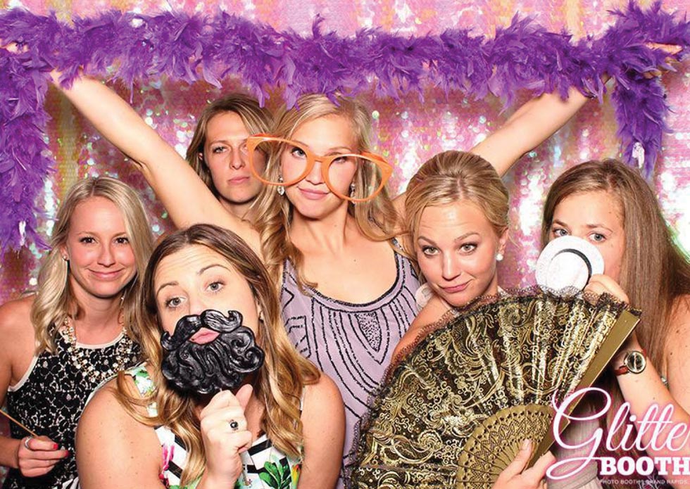 group of people using props in a photo booth at a wedding
