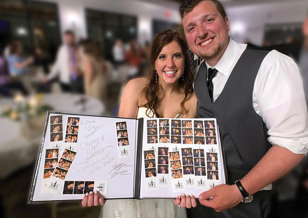 bride and groom showing off a book of all the photo booth photos from their wedding