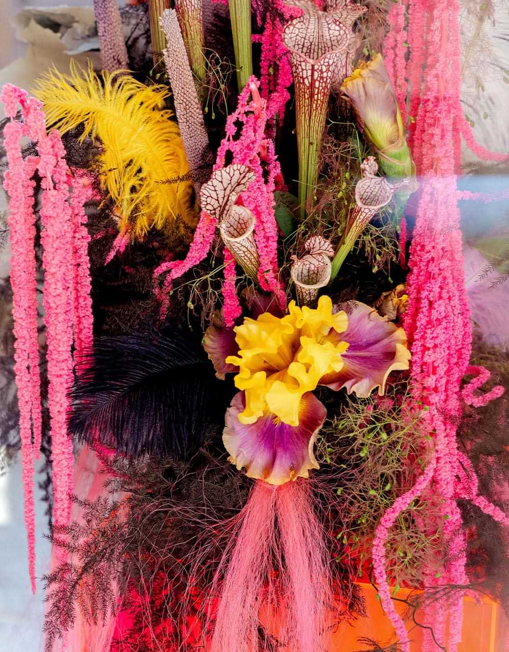 a vibrant and avant garde arrangement with exotic purple pink and yellow flowers along with along with non-floral elements