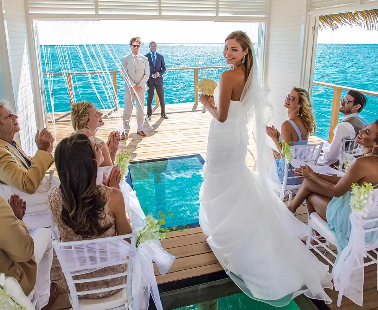 a bride walks down the aisle of a wedding ceremony held in a over-water bungalow
