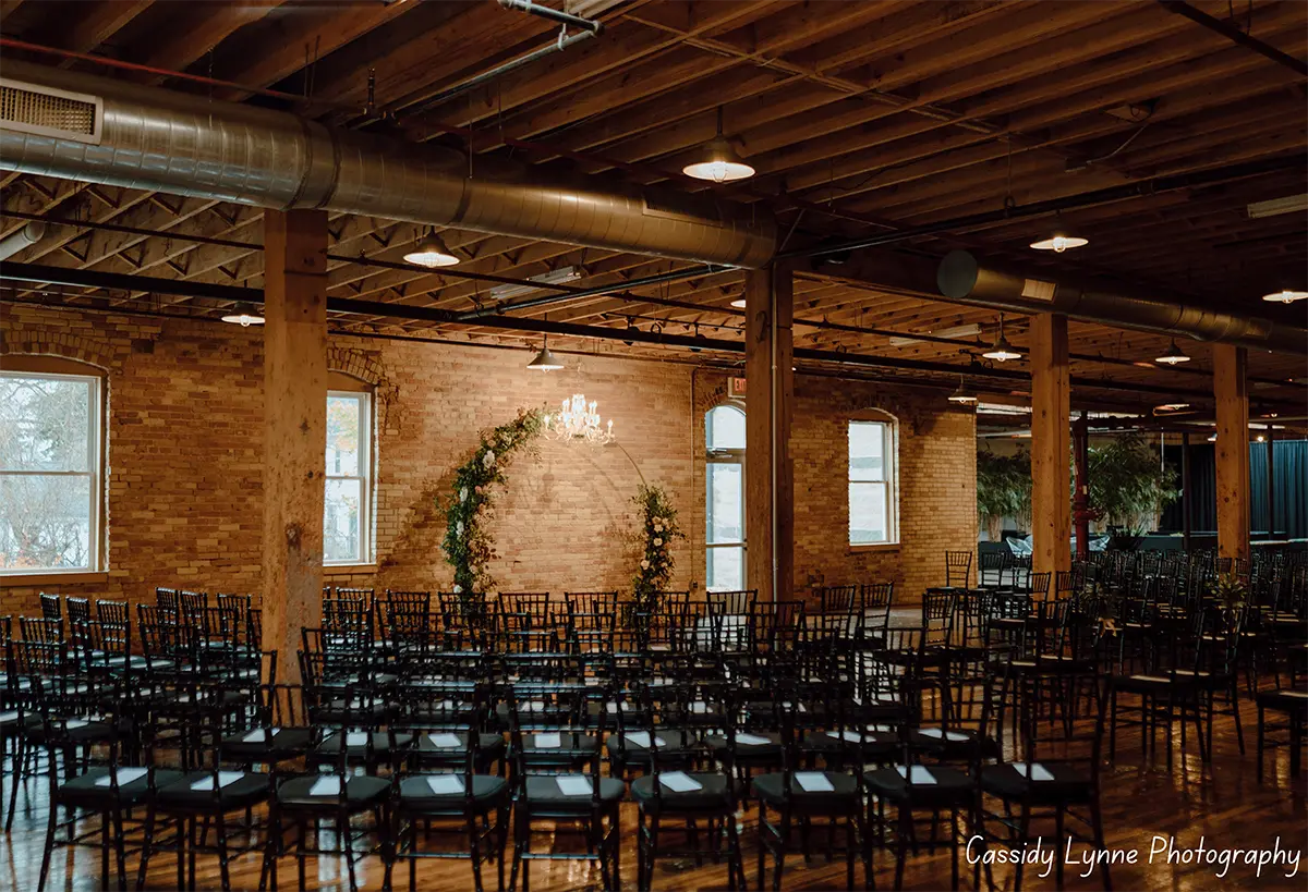 Room area filled with many chairs and a chandelier lit up nearby a brick wall inside at The Goei Center venue