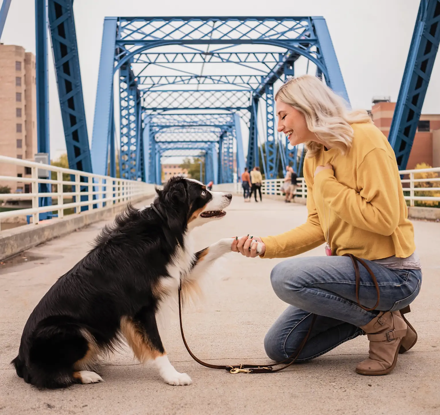 Woman kneeling with dog near bridge