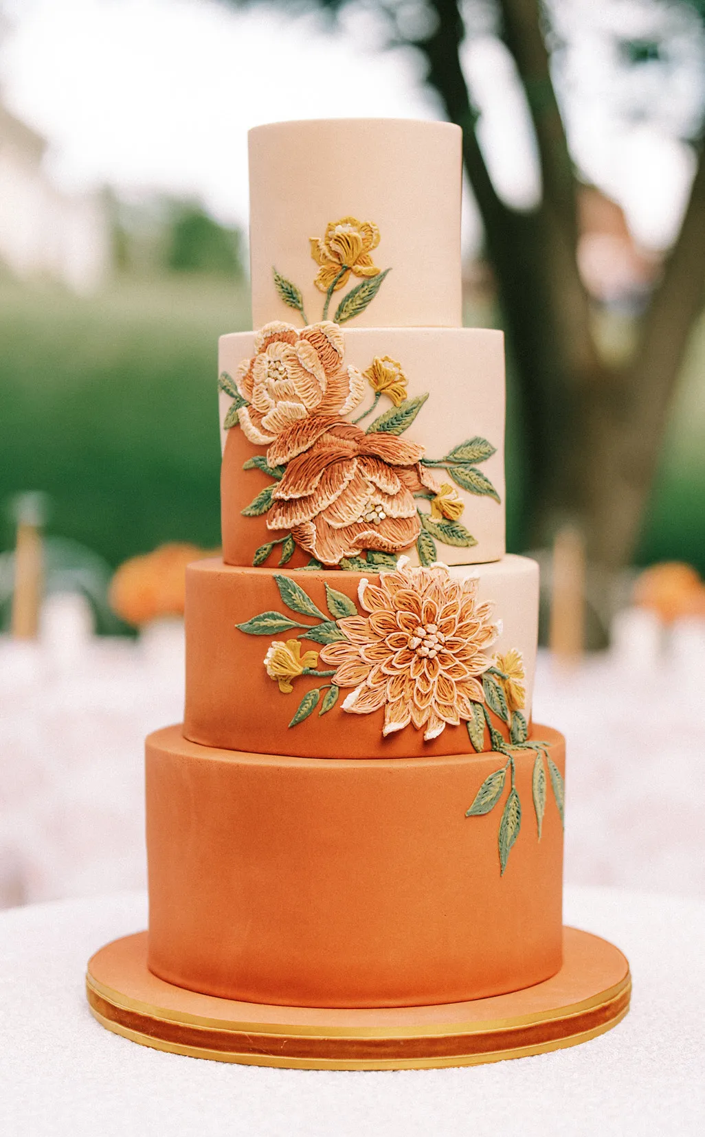 Four tiered orange and pink wedding cake with flowers