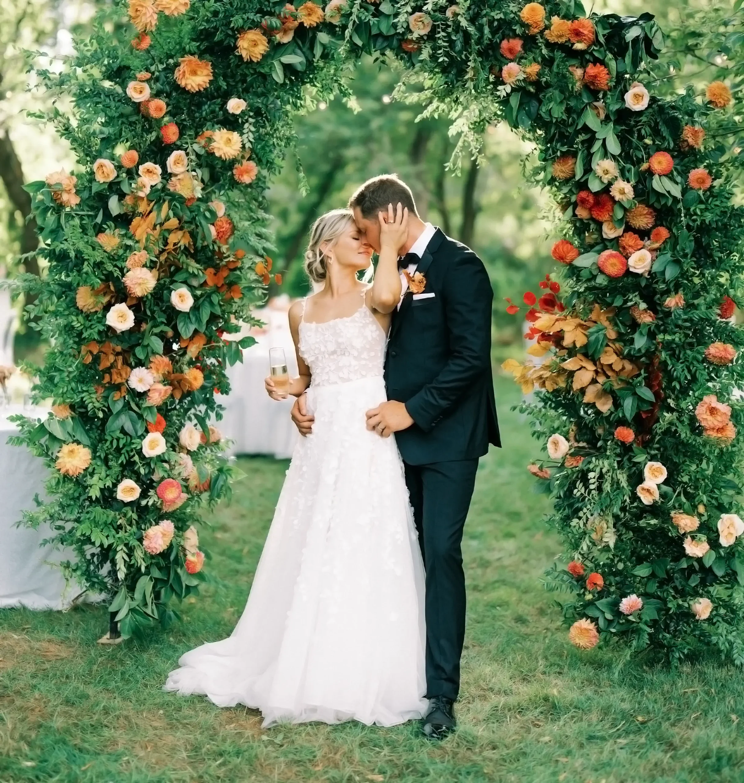 Samantha and sean standing under flowers embracing