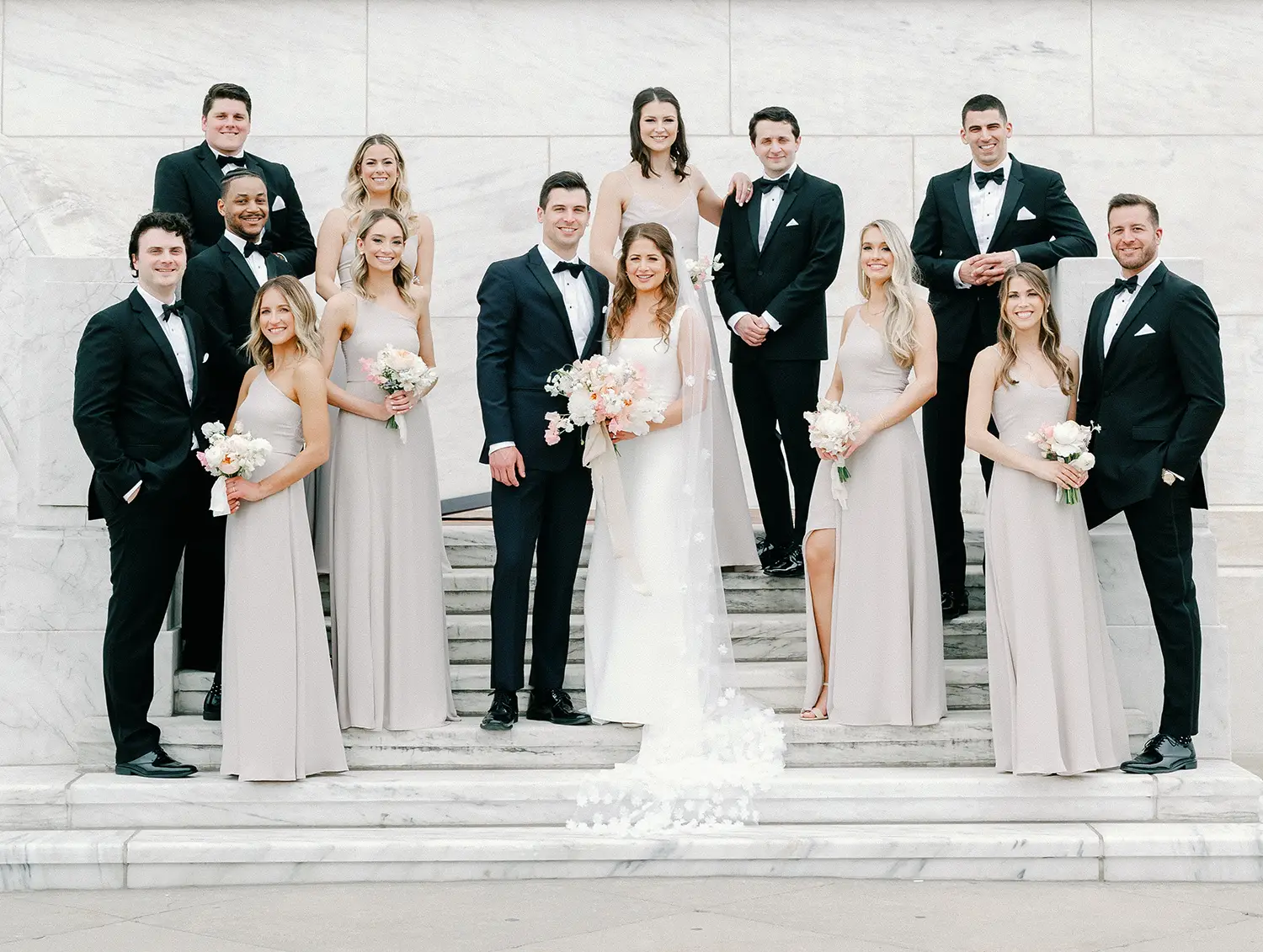 Abbey and Joe posing with their bridesmaids and groomsmen on marble steps