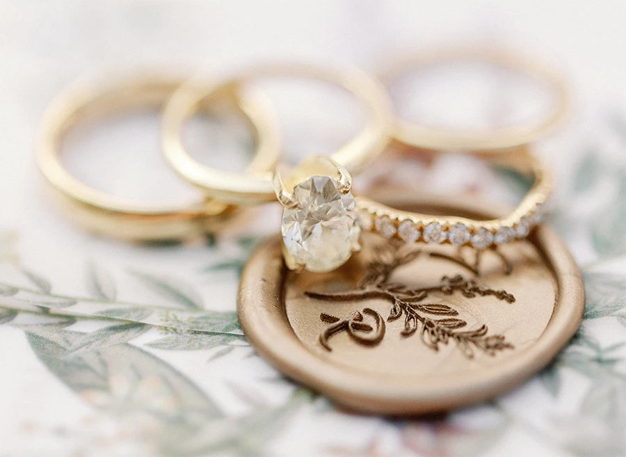 Gabrielle and Riley's wedding rings on top of a wedding invitation