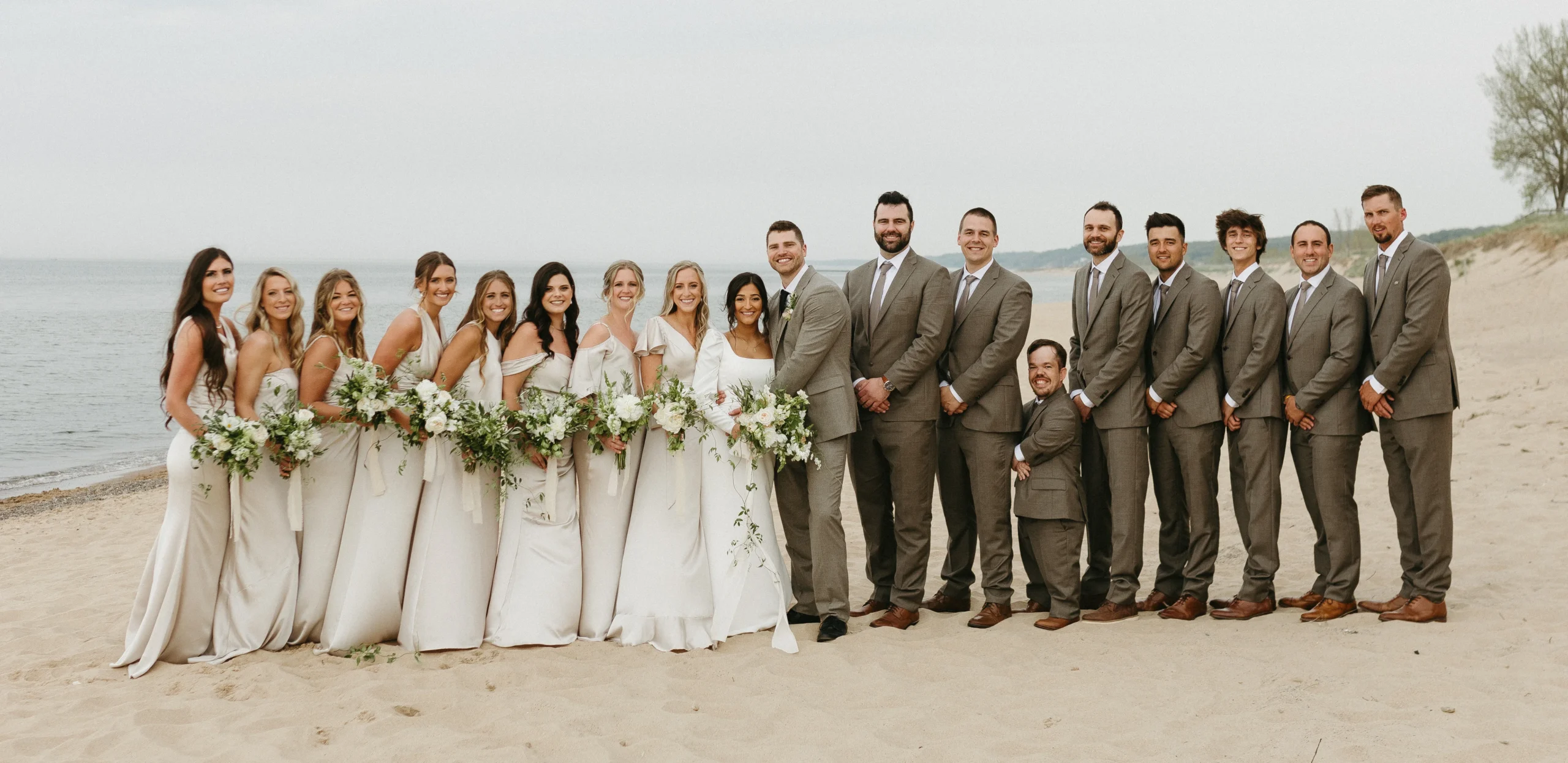group photo on the beach with bride, groom, groomsmen, and bridesmaids
