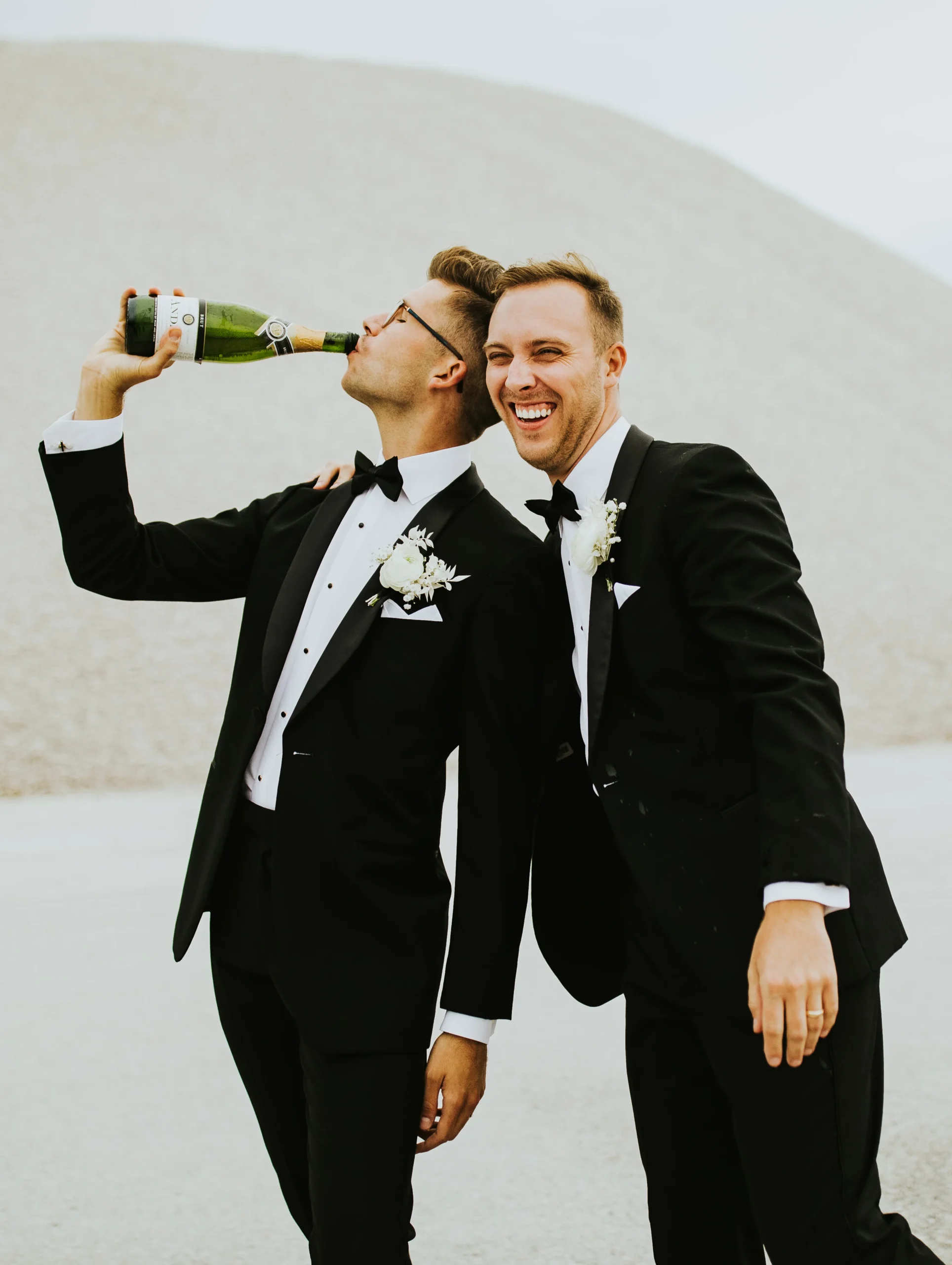 two men wearing tuxes posing for picture