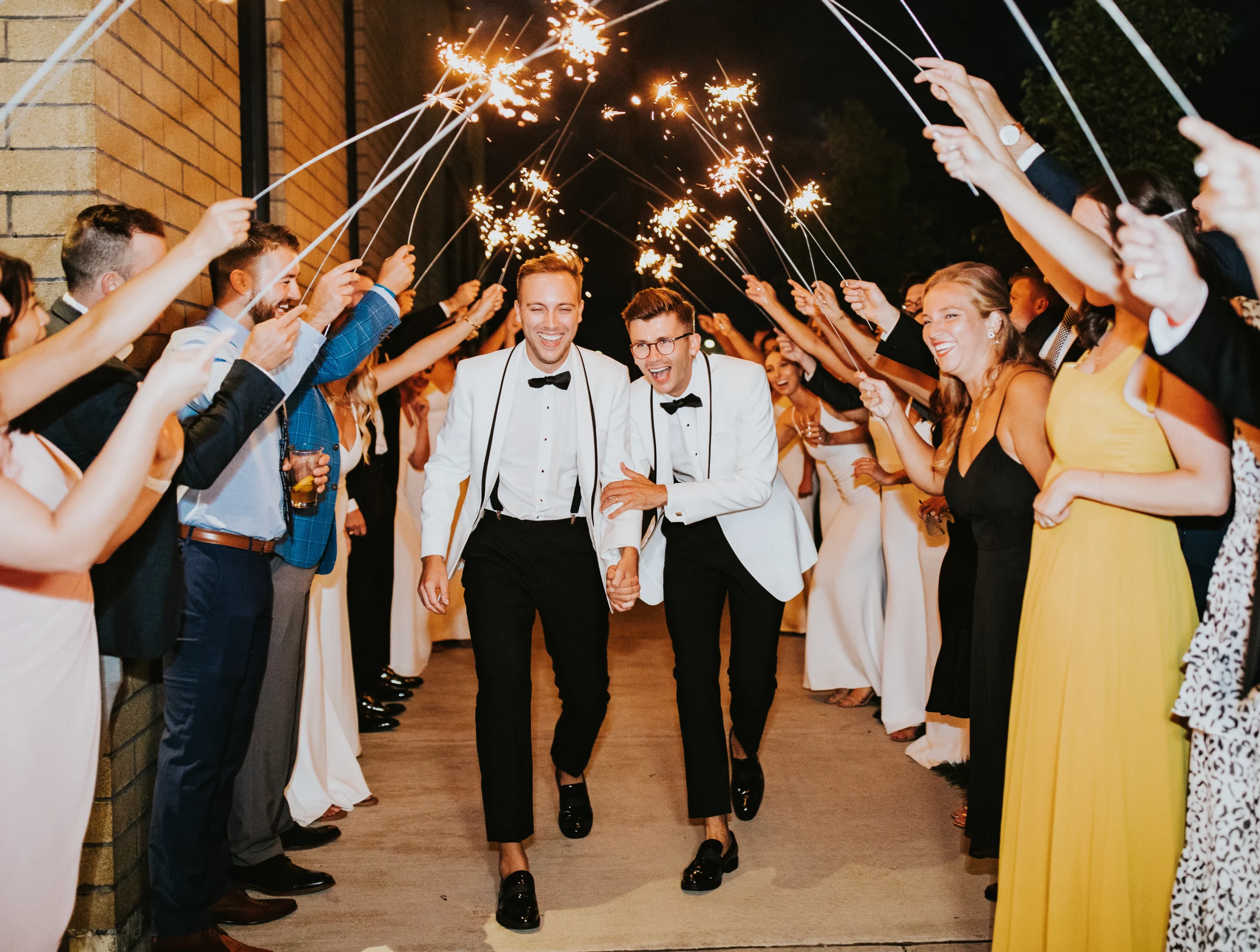 Byron and Kyle walking through a crowd holding up sparklers 