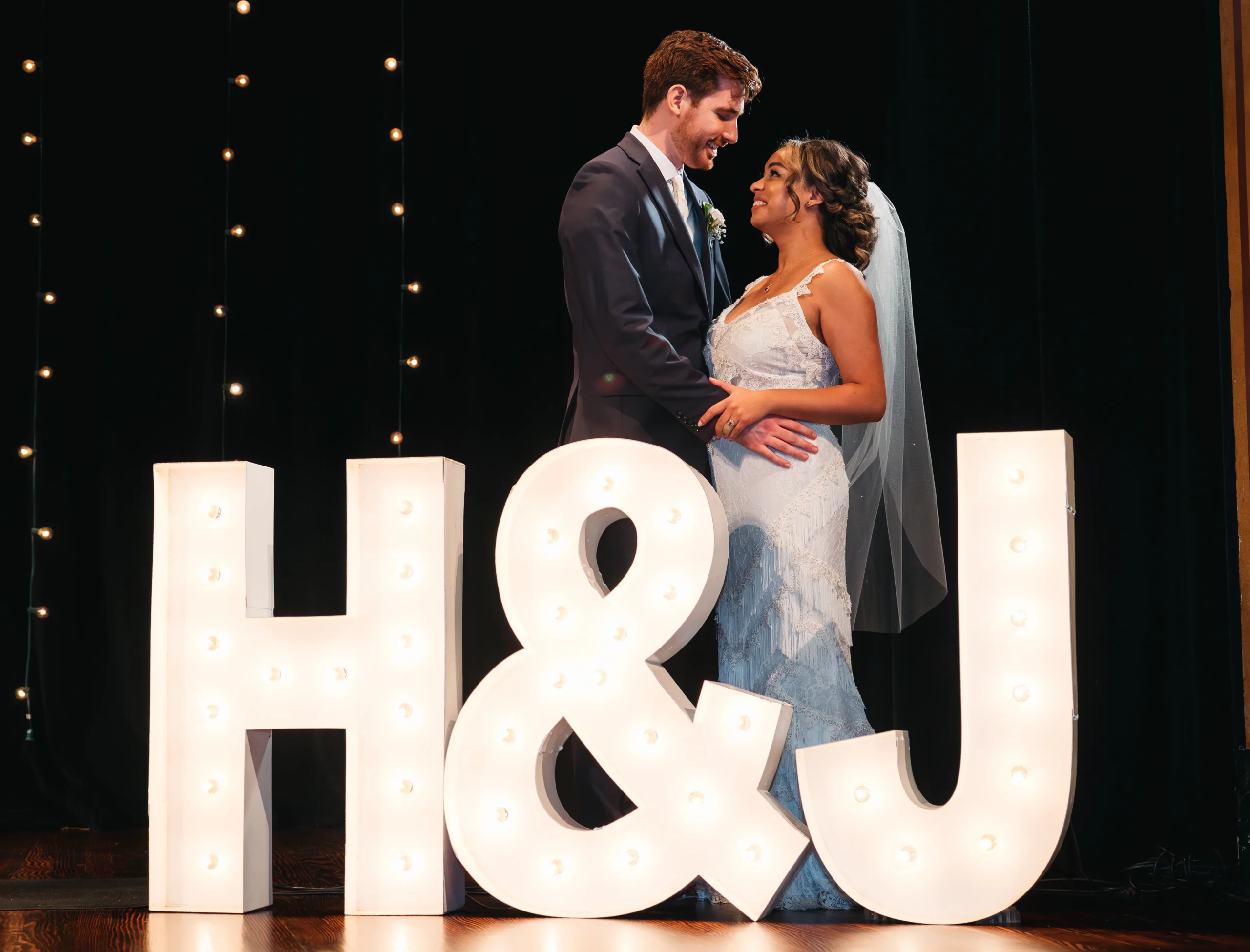 Bride and groom standing behind giant letters that read 'H&J'