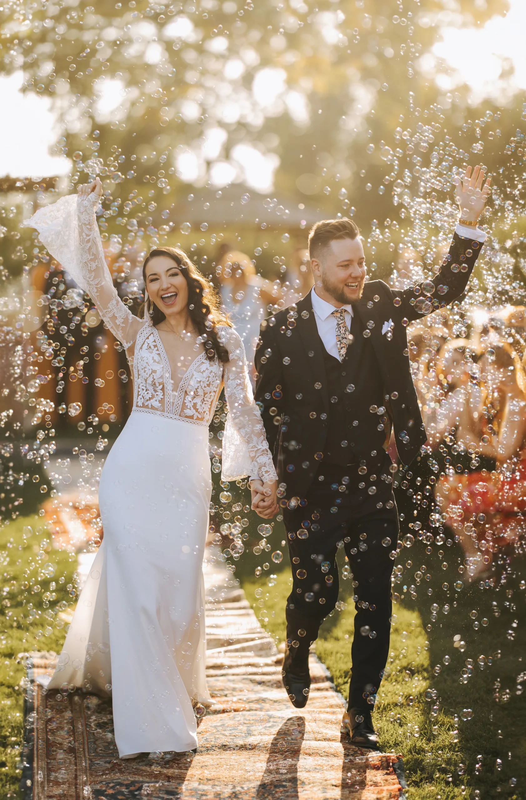 bride and groom holding hands walking down aisle with bubbles in the air