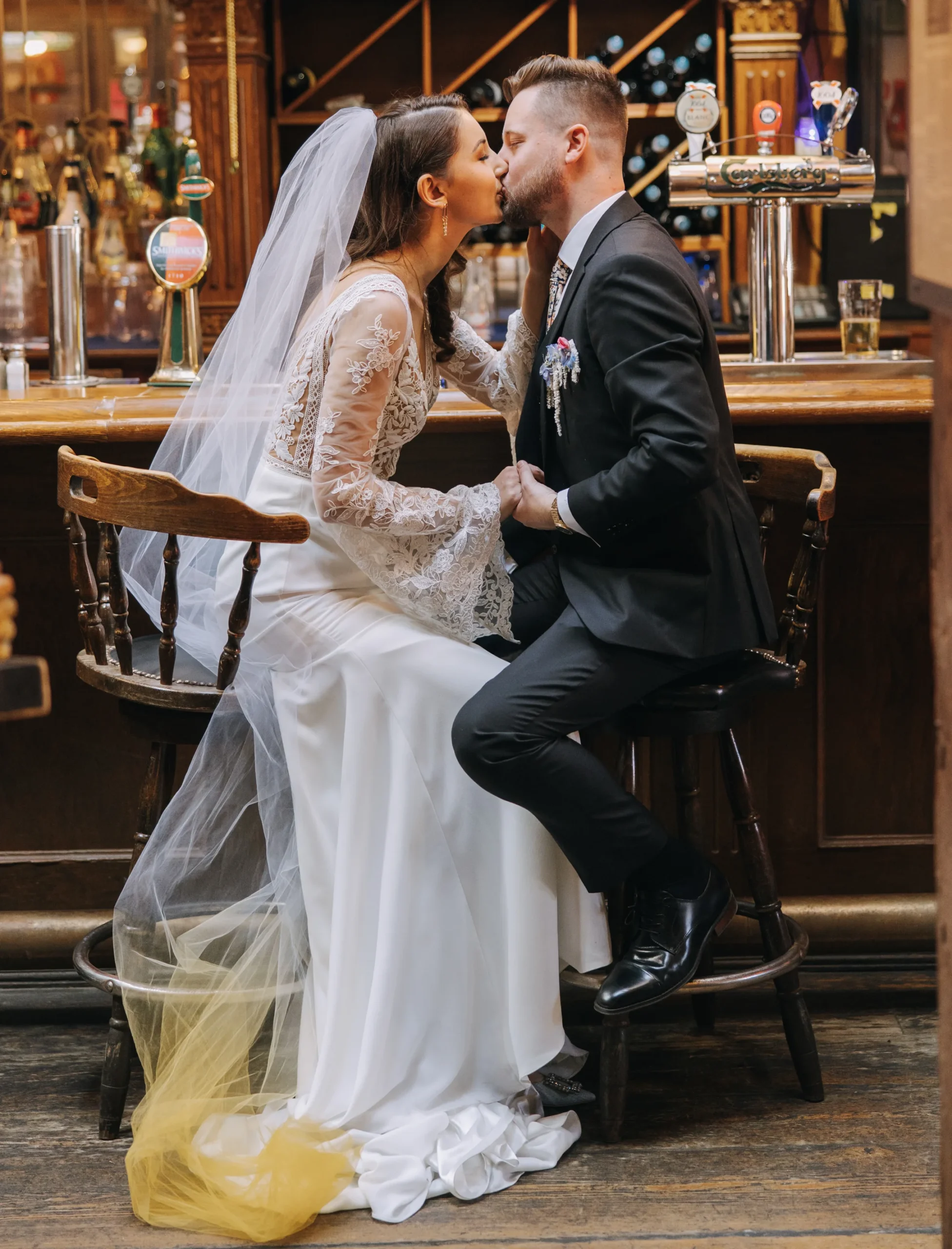 bride and groom sitting on bar stools kissing