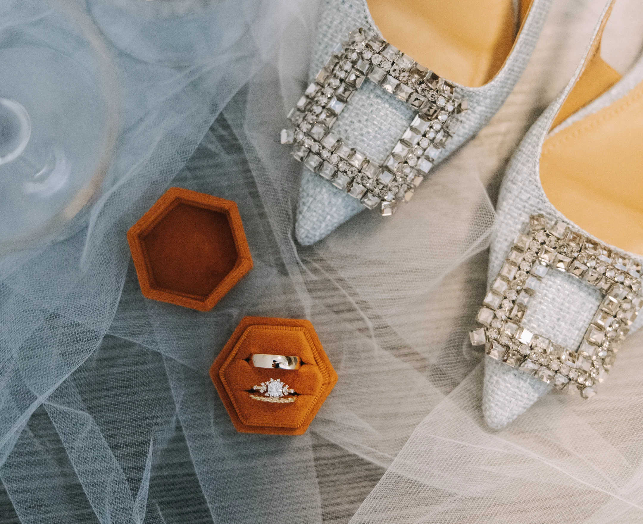 heels and rings sitting on top of a veil 