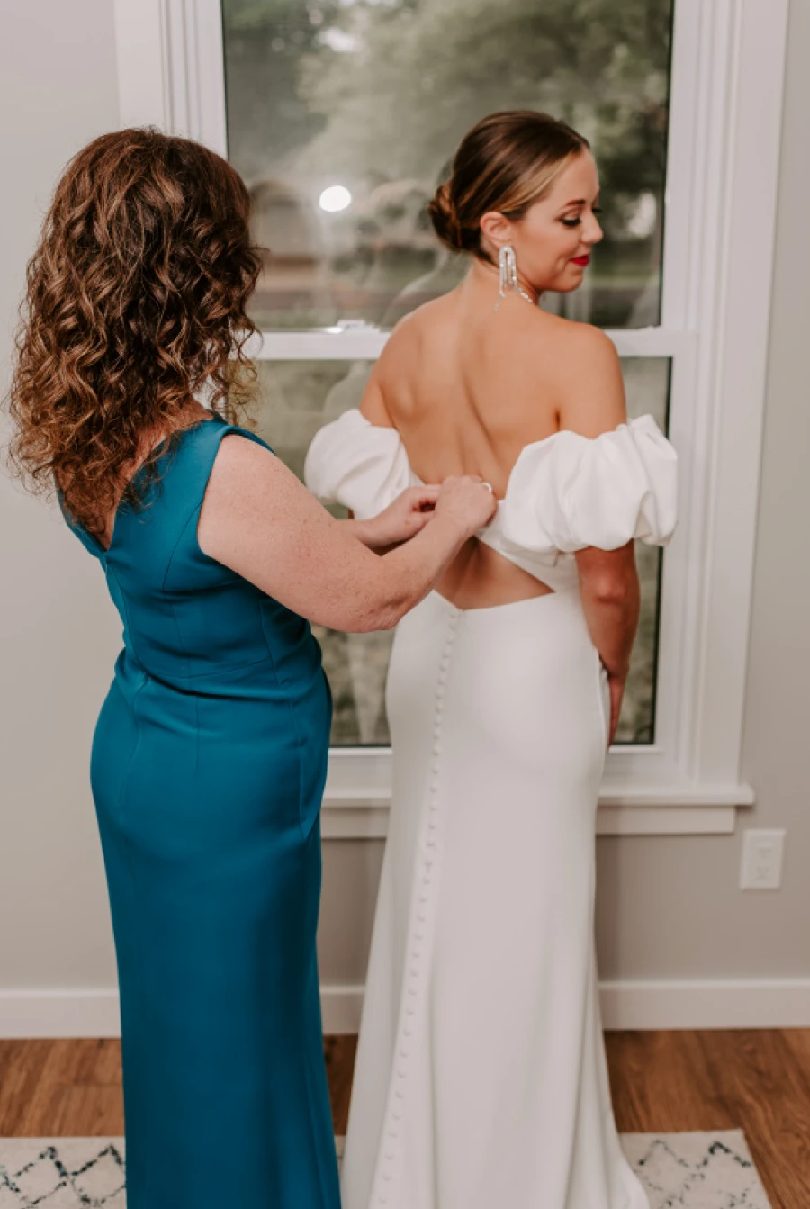 bridesmaid helping bride zip up wedding dress