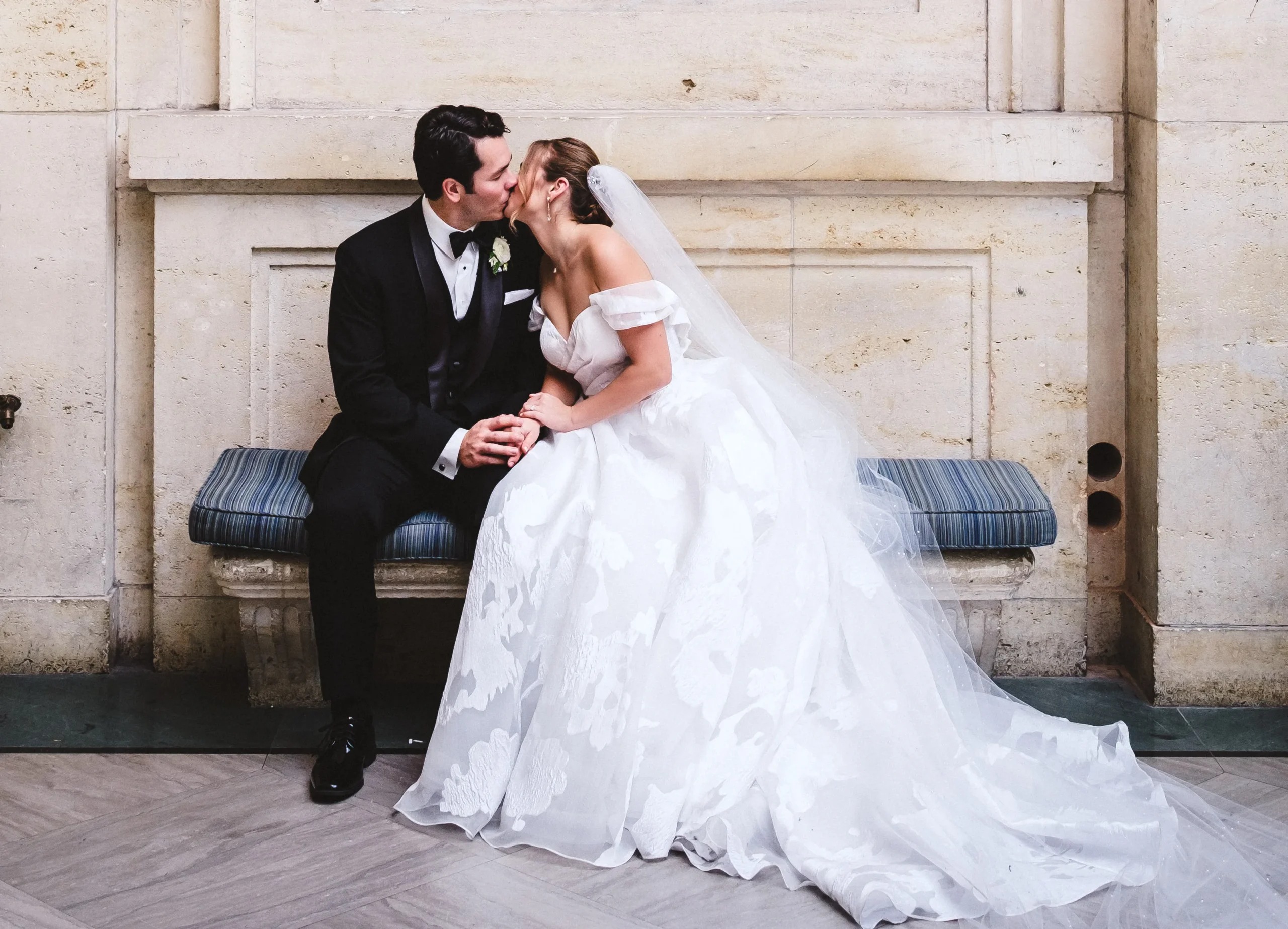 bride and groom kissing on a bench