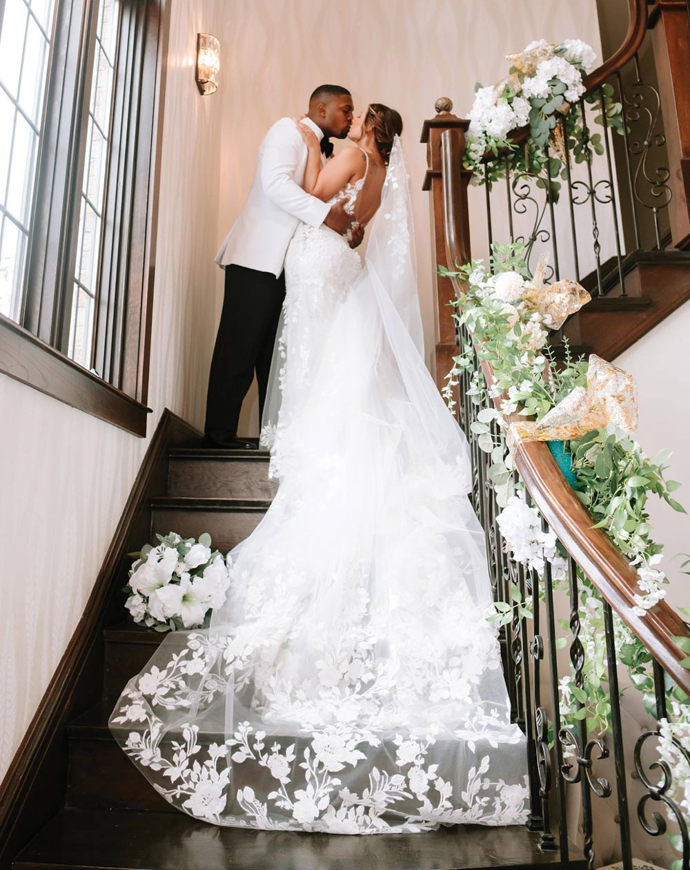 bride and groom kissing at the top of a staircase