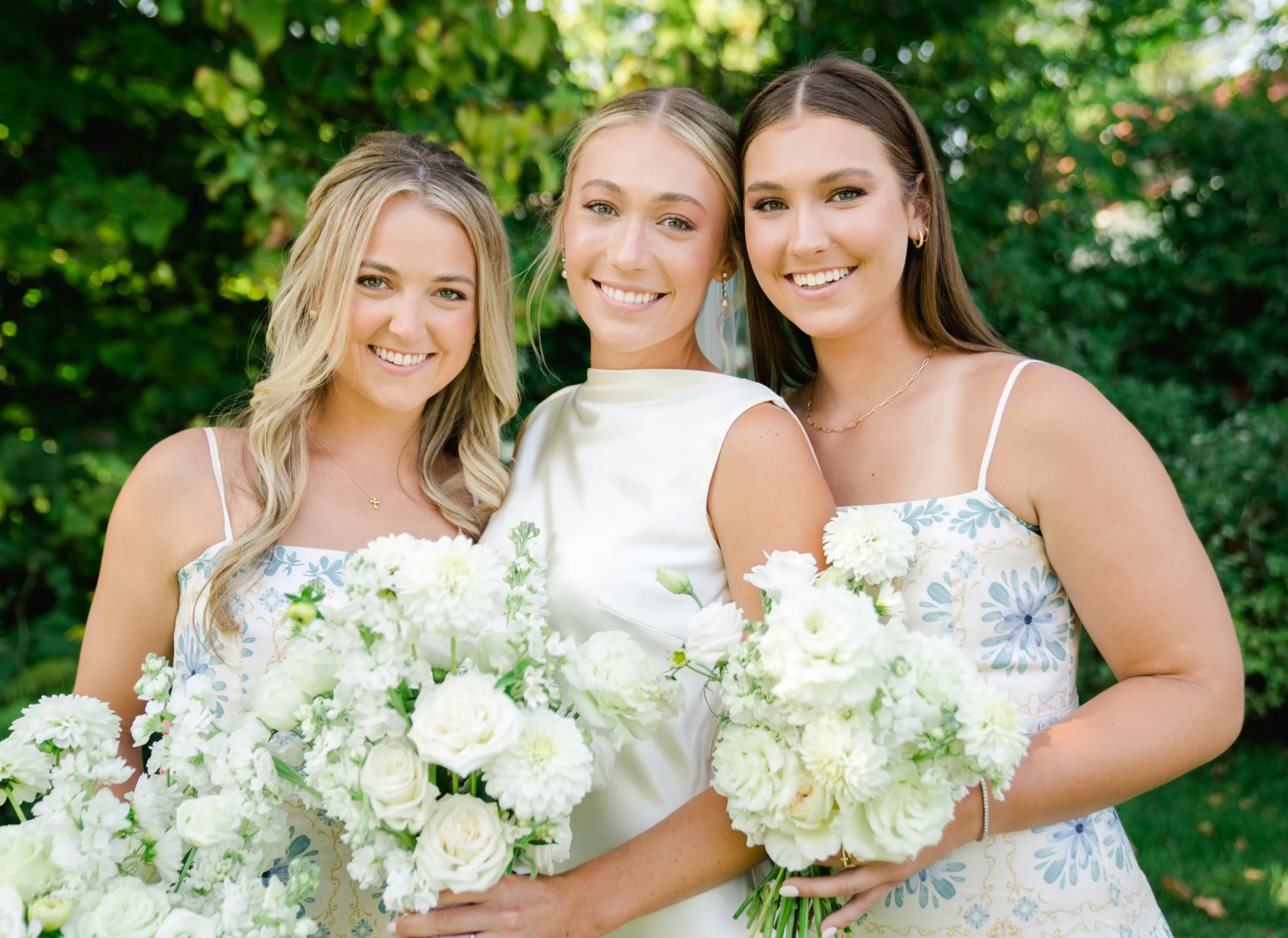 three women in dresses holding white bouquets 